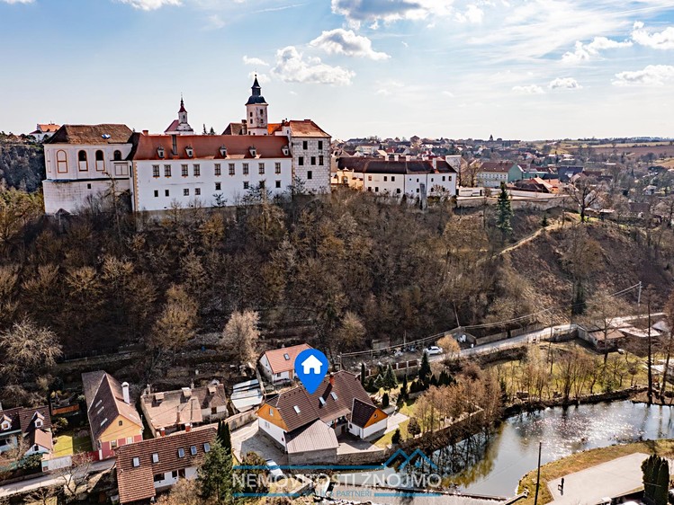 Letecký pohled na dům u řeky pod historickým zámkem ve Znojmě.