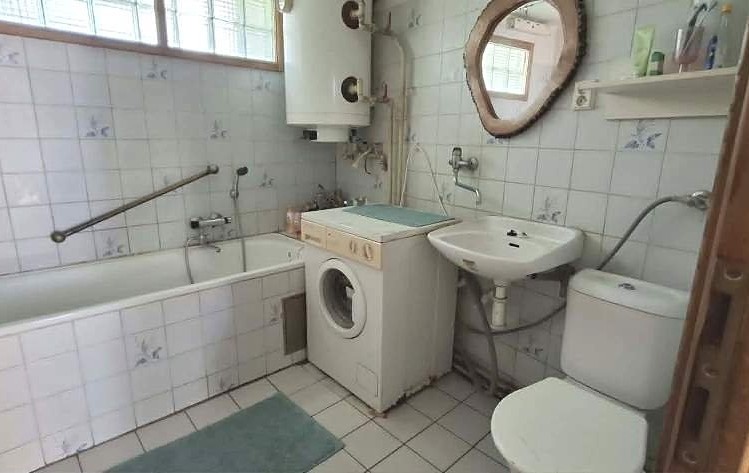 Koupelna s vanou, pračkou, umyvadlem a toaletou.