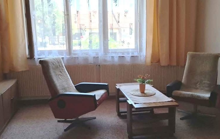 Posezení se dvěma křesly a konferenčním stolkem u okna v obývacím pokoji.